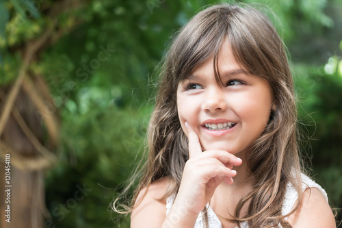 Smiling attractive little girl peeks up. Girl's hand supporting cheek. 
