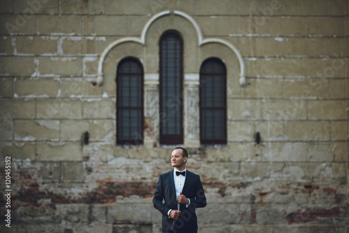 happy and handsome groom standing outside