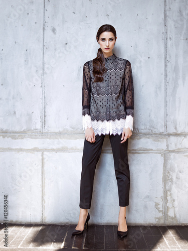 Fashion model wearing black lace shirt and trousers posing in studio