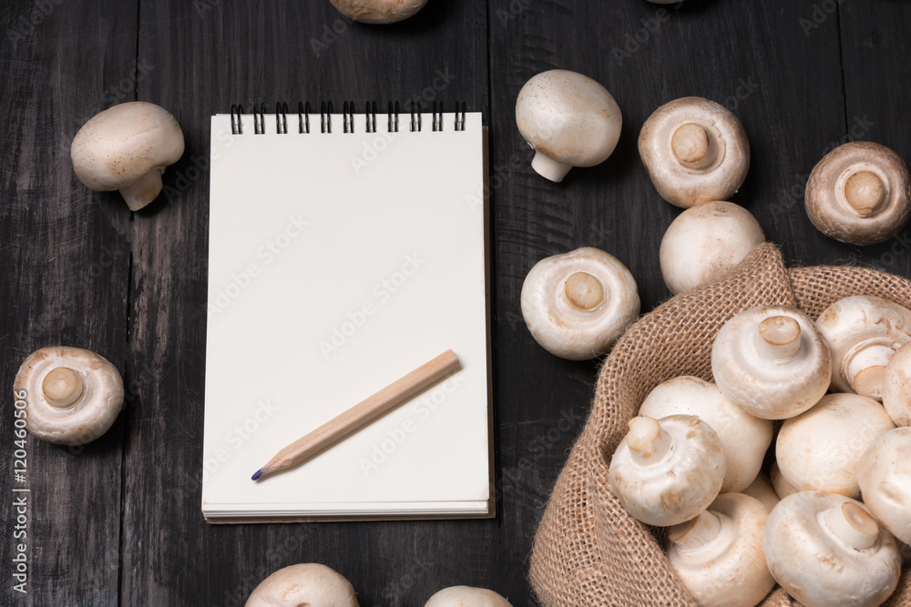 Fresh champignons mushrooms in bag with white note on the wood black table