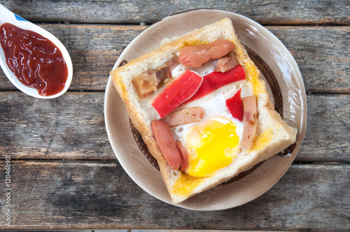 Egg, hotdog and crab stick in a hole of a slice of bread eat wit photo