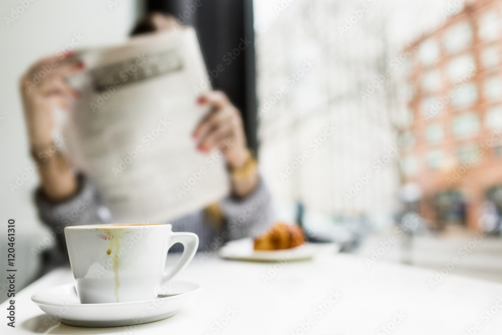 Woman reading newspaper while having breakfast at coffee shop Woman reading newspaper while having breakfast at coffee shop