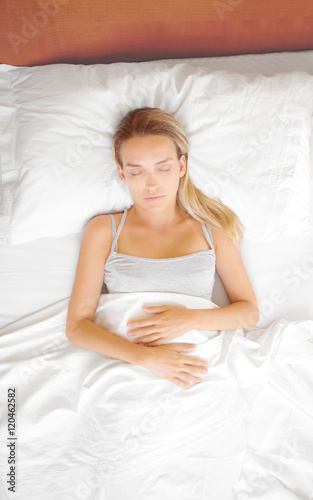 Donna dorme a letto con lenzuola bianche