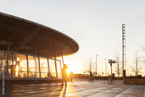 Silhouette person walking outside modern building during sunset