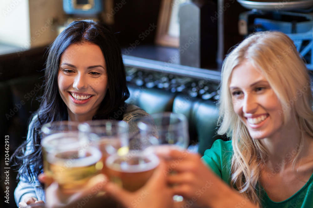 happy female friends drinking beer at bar or pub