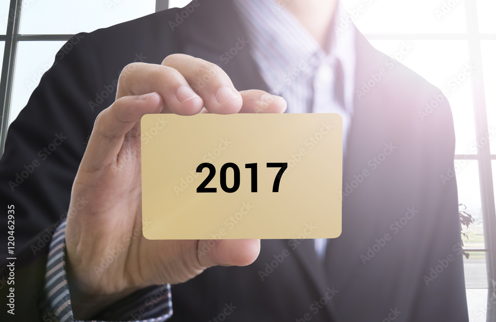 businessman hand holding a business card with a message Happy New Year 2017 concept advertise. businessman hand holding a business card with a message Happy New Year 2017 concept advertise.