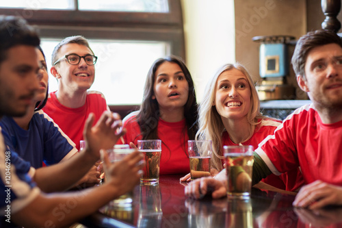 fans or friends watching football at sport bar