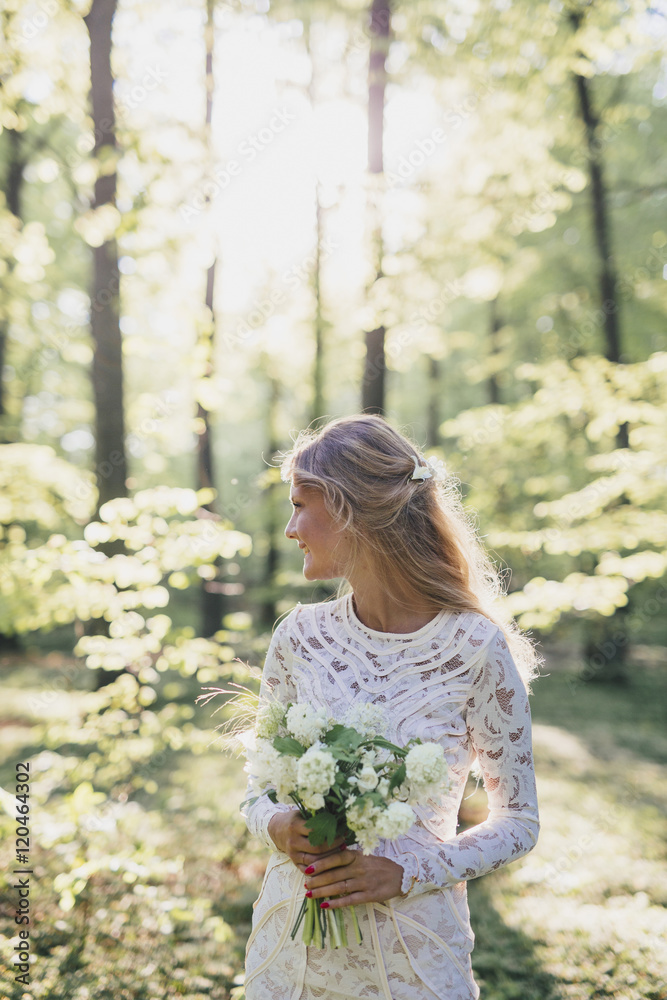 Beautiful bride holding bouquet in forest Beautiful bride holding bouquet in forest