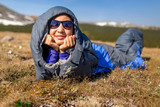 The tourist woman hiker in a sleeping bag on a grass in mountain