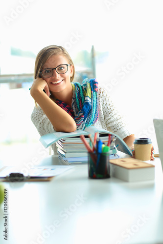 Happy student girl sitting with pile of books