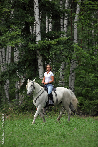 Beauty blond girl riding horse in woods 