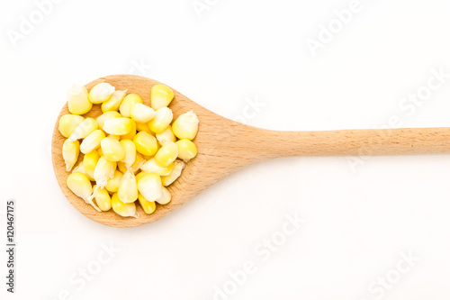 Corn kernels in wooden spoon, on white background.