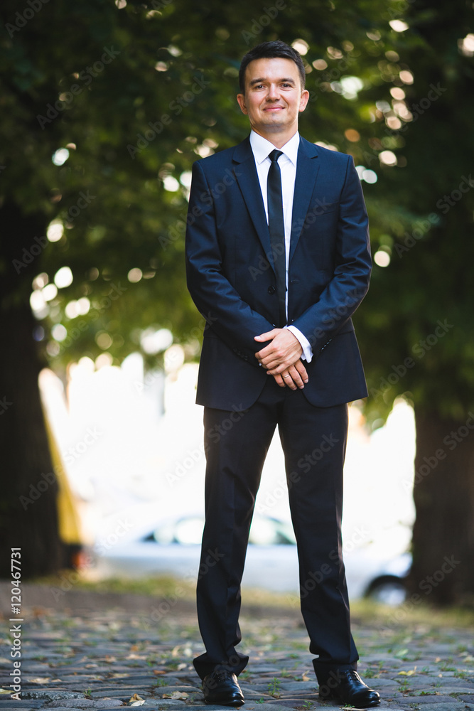 attractive and young groom standing in the green garden attractive and young groom standing in the green garden