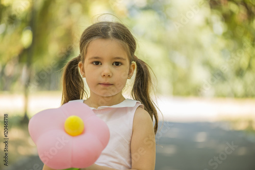 Adorablr little girl holding flower shape balloon outdoors in summer park. Birthday party. Childhood. Happiness. photo