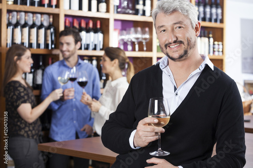Man Holding Wineglass While Friends Communicating In Shop