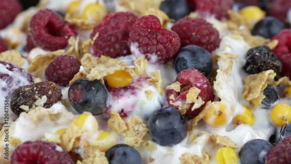Cereal flakes with blueberries, raspberries and sea buckthorn rotating . Crunchy tasty muesli food background close-up. Cereals, berry and dried food mixed for breakfast . Cereal flakes with blueberries, raspberries and sea buckthorn rotating . Crunchy tasty muesli food background close-up. Cereals, berry and dried food mixed for breakfast .