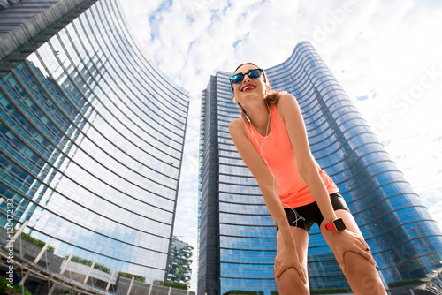 Portrait of a young sports woman outdoors on the modern skyscrapers background. Healthy lifestyle in Milan city.