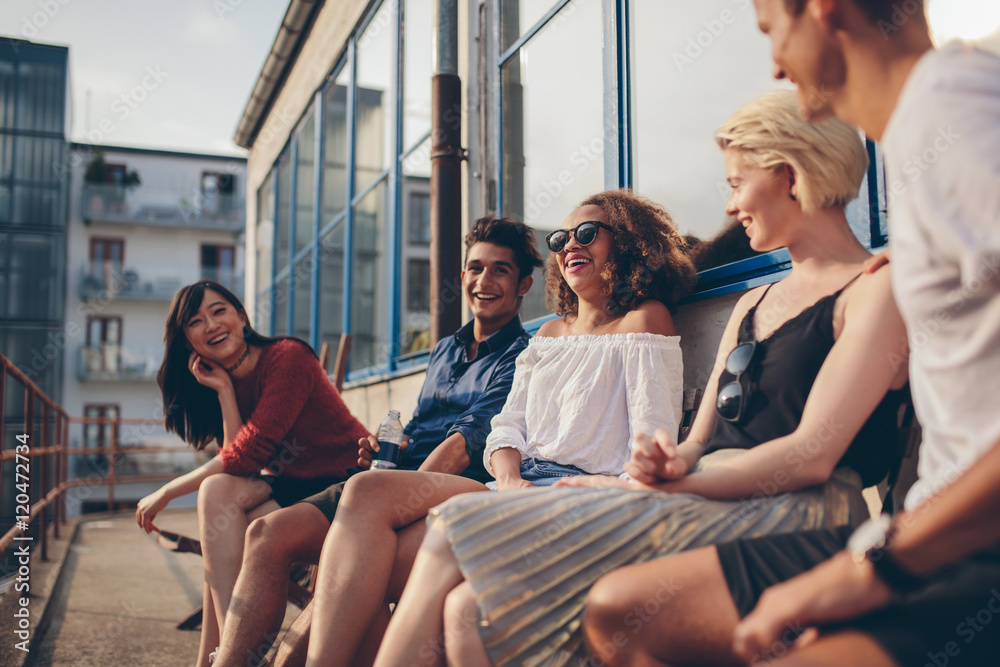 Multiracial group of friends sitting in balcony and smiling - obrazy, fototapety, plakaty 
