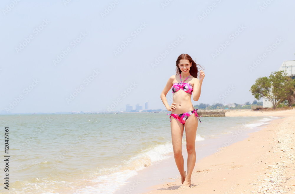 Beautiful women in bikinis strolling happily along the beach.