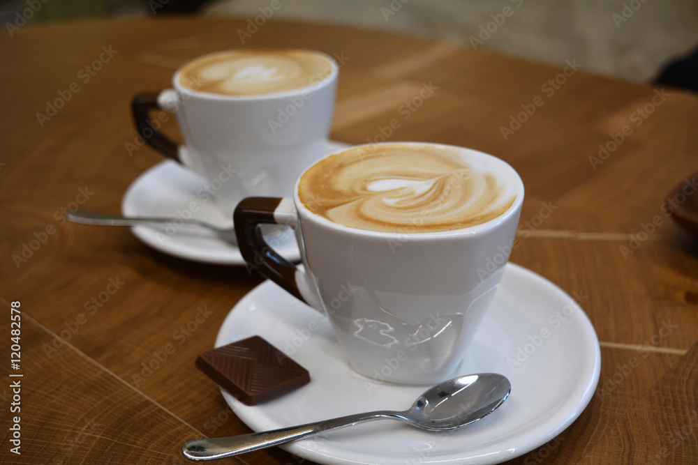 Fototapeta Cup of foamy cappuccino on a wooden table