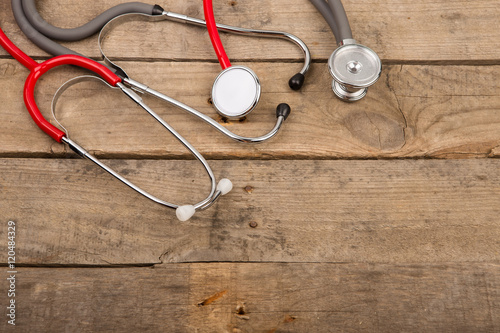 Grey and red stethoscopes on wooden desk