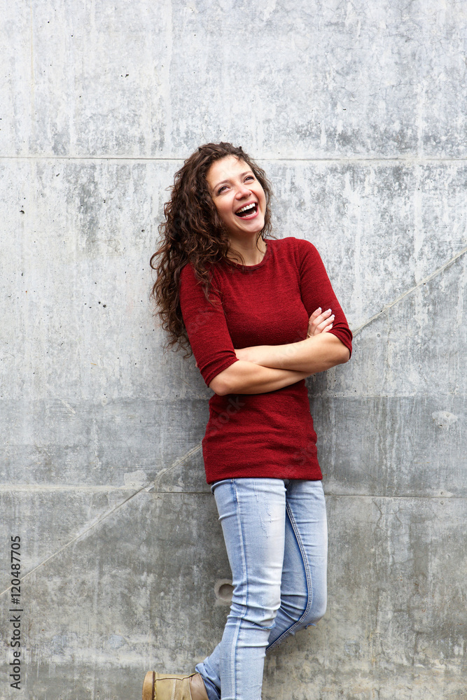 Confident young woman standing against gray wall Confident young woman standing against gray wall