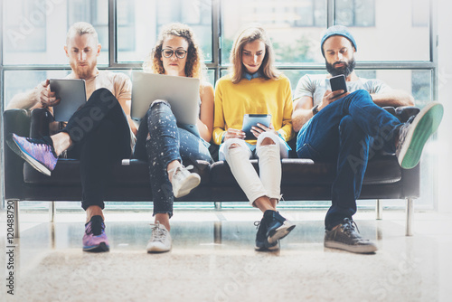 Group Adult Hipsters Friends Sitting Sofa Using Modern Gadgets.Business Startup Friendship Teamwork Concept.Creative People Working Together Marketing Project.Coworking Process Office Studio.Blurred.