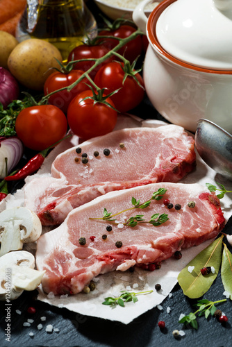 two pieces of raw pork and fresh ingredients for soup, closeup