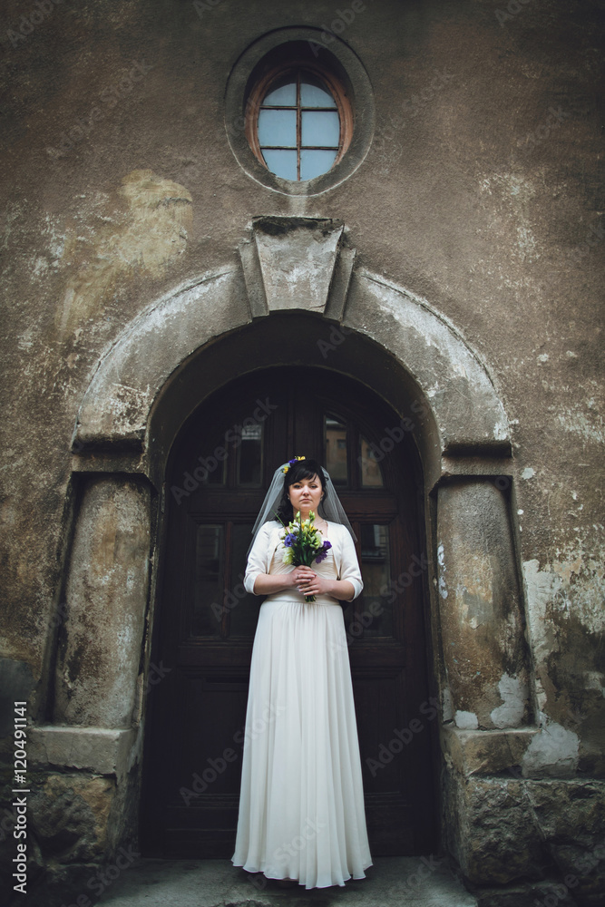 Beautiful innocent  bride in white dress posing near church
