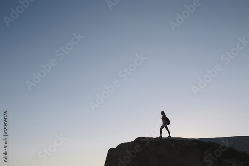 silhouette young woman tourist with backpack standing on cliff
