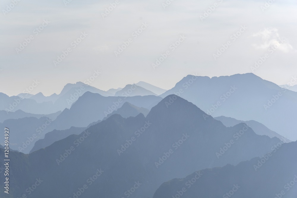 Silhouette of blue mountains in the fog. View of Moldoveanu peak, the highest peak from Romanian Carpathian Mountains range. Seamless background.