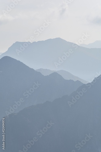 Silhouette of blue mountains in the fog. View of Moldoveanu peak, the highest peak from Romanian Carpathian Mountains range. Seamless background.