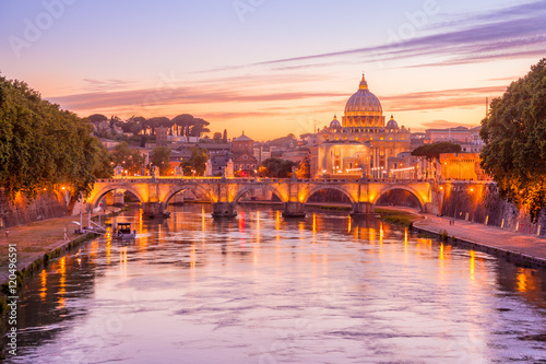 Skyline of Rome in a magenta twilight with San Pietro basilica, at Sant'Angelo bridge and Tevere river illuminated by city lights of Roma in Italy