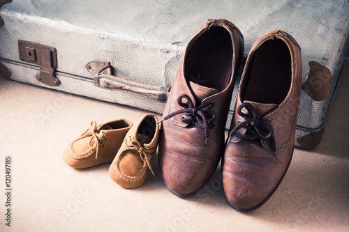 Old adult leather shoes and kid shoes with old suitcase, Travel together or father's day concept