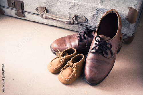 Old adult leather shoes and kid shoes with old suitcase, Travel together or father's day concept
