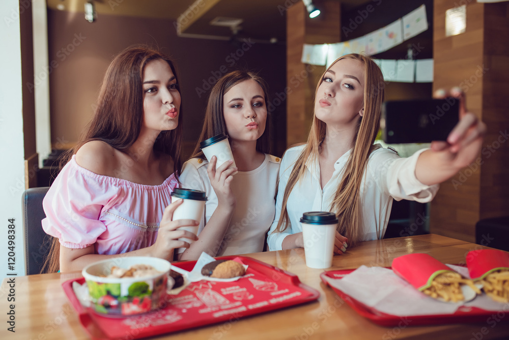 Three young girls are doing selfie in fast food restaurant Three young girls are doing selfie in fast food restaurant