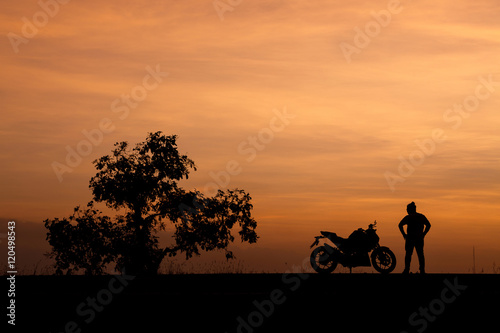 Silhouette man and his motorcycle To live a lifestyle. with beautiful the sky at sunset..Background,