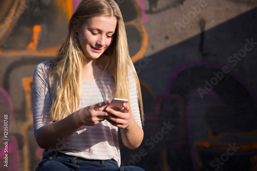 Teenage Girl Texting On Mobile Phone In Playground