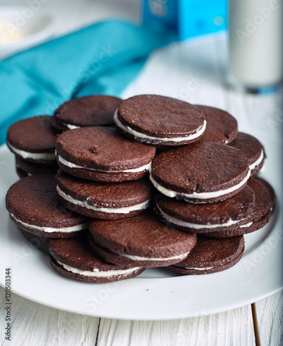 Chocolate sandwich cookies with cream filling on wood background.