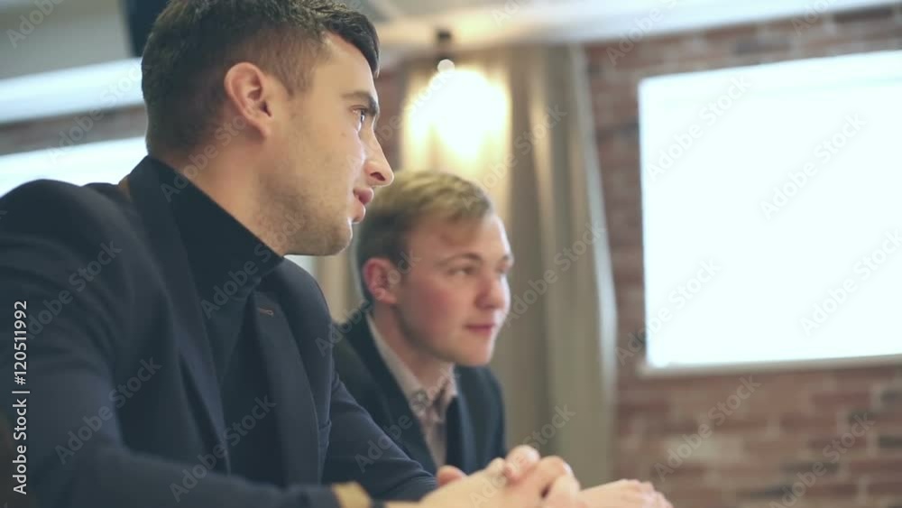Young businessmen seating at a table and talking.
