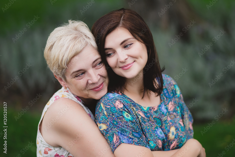Mother and adult daughter in a green park posing together Mother and adult daughter in a green park posing together