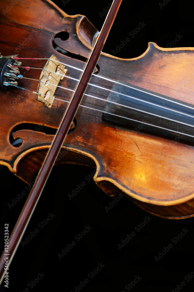 Fototapeta premium Old wooden violin and bow on isolated background. Violinist playing an Vintage fiddle. Beautiful classical music string instrument. An orchestral Symphony at the concert.