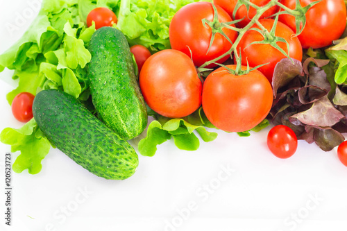 Different bright vegetables on a white background. Tomato, cucumber and lettuce.