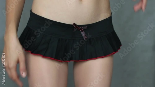 Close up view of the shapely body of a young woman in a short sexy black mini skirt