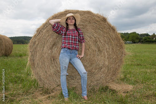 фотографія Full length portrait of beautiful countrywoman standing next to hay stack
