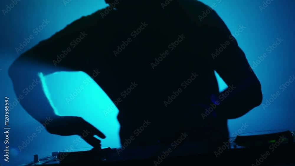 Backlit DJ Playing Music in Nightclub. Silhouette of a DJ. Shot on RED Cinema Camera in 4K (UHD). Backlit DJ Playing Music in Nightclub. Silhouette of a DJ. Shot on RED Cinema Camera in 4K (UHD).