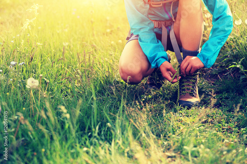 woman hiker tying shoelace on grassland grass..