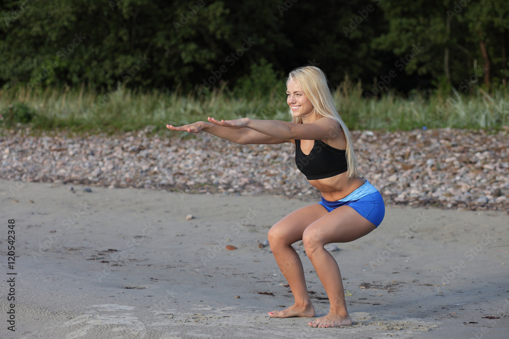 Naklejka premium sporty girl on the beach squats and workout