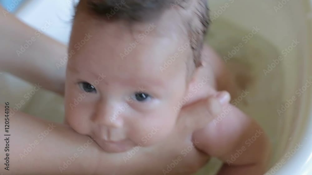 Happy baby infant is swimming in bath on the mother hands
Happy baby infant is swimming in bath on the mother hands