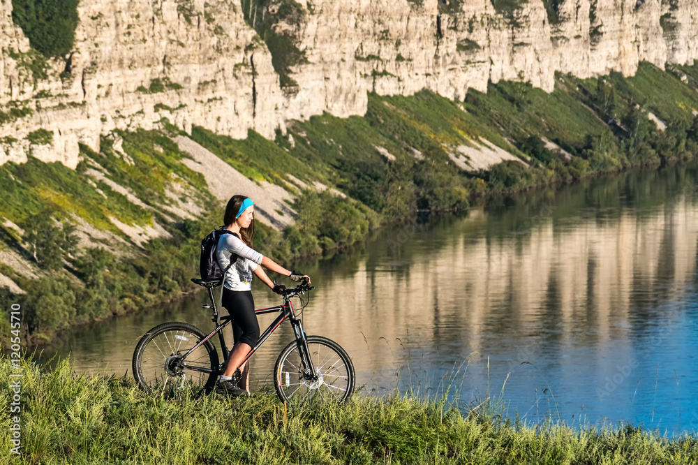 Fototapeta premium girl standing with bicycle on a background of cliff